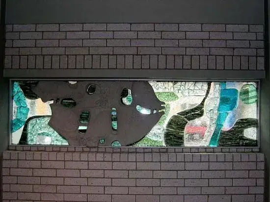 Glas-in-betonraam met een vis van beton in een zee van gekleurd glas